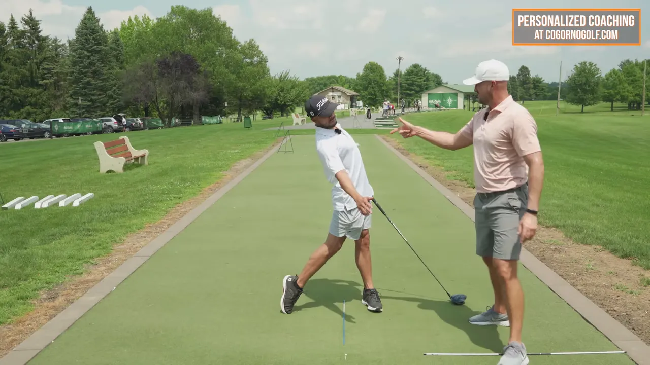 Coach pointing as the student demonstrates a head-back finish and extended arms during the driver follow-through