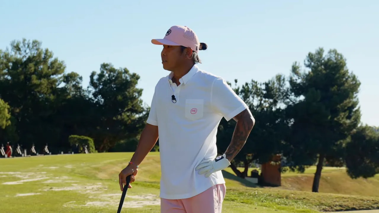 Golfer on a practice range holding a club and looking downrange, clear lighting and crisp detail