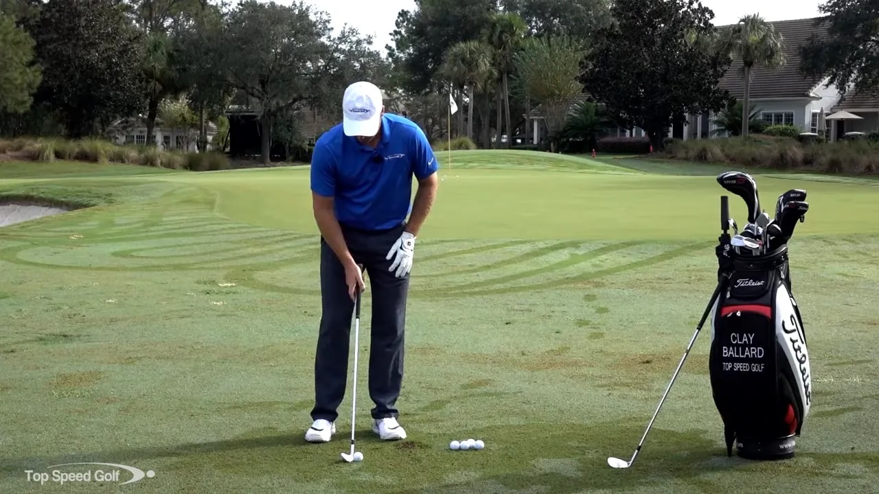 Instructor demonstrating a chip setup with a narrow stance, slight forward shaft lean and the club addressing the ball on the fairway.