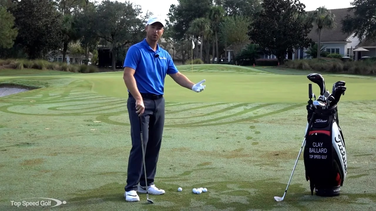 Instructor on the practice area with golf bag, balls, and a wedge demonstrating short-game choices in front of a green