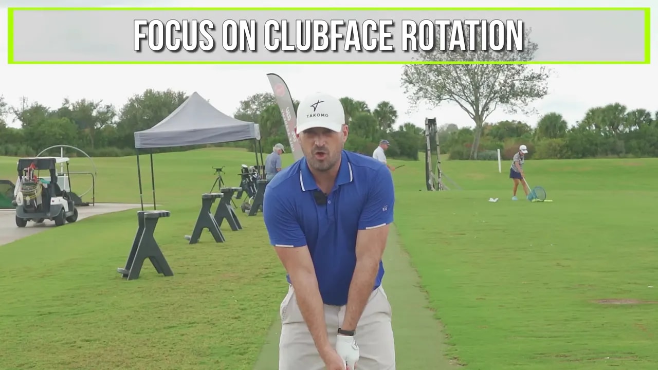 Instructor facing the camera demonstrating lead-arm rotation with a large on-screen graphic reading 'FOCUS ON CLUBFACE ROTATION'