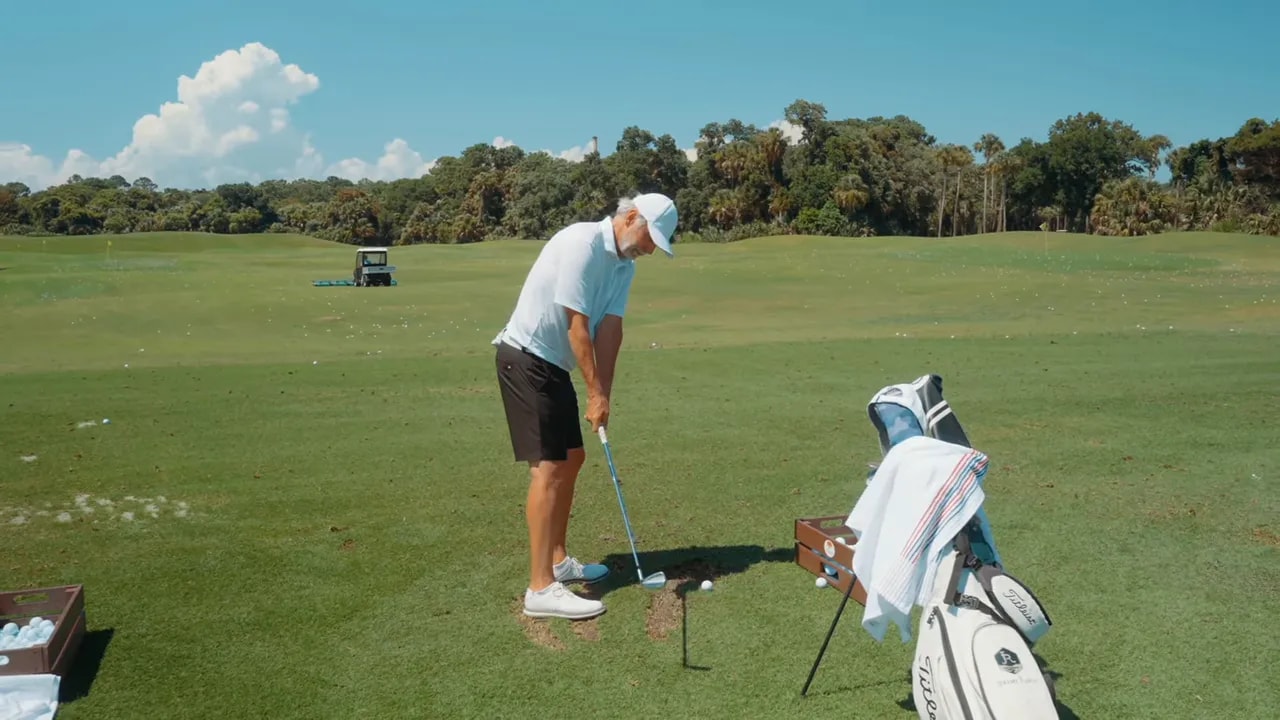 golfer at address with proper forward tilt and hands positioned ahead of ball on driving range