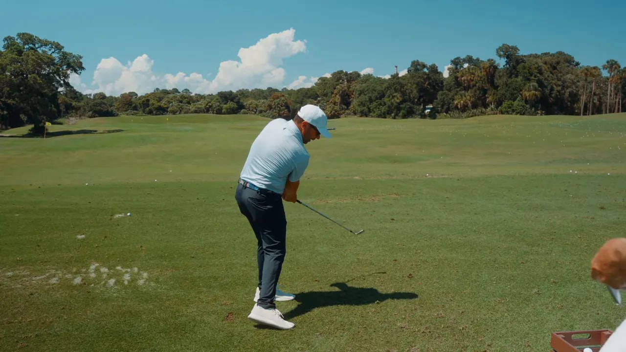 Golfer in the downswing with hands leading and head slightly behind the hands demonstrating a shallow attack angle