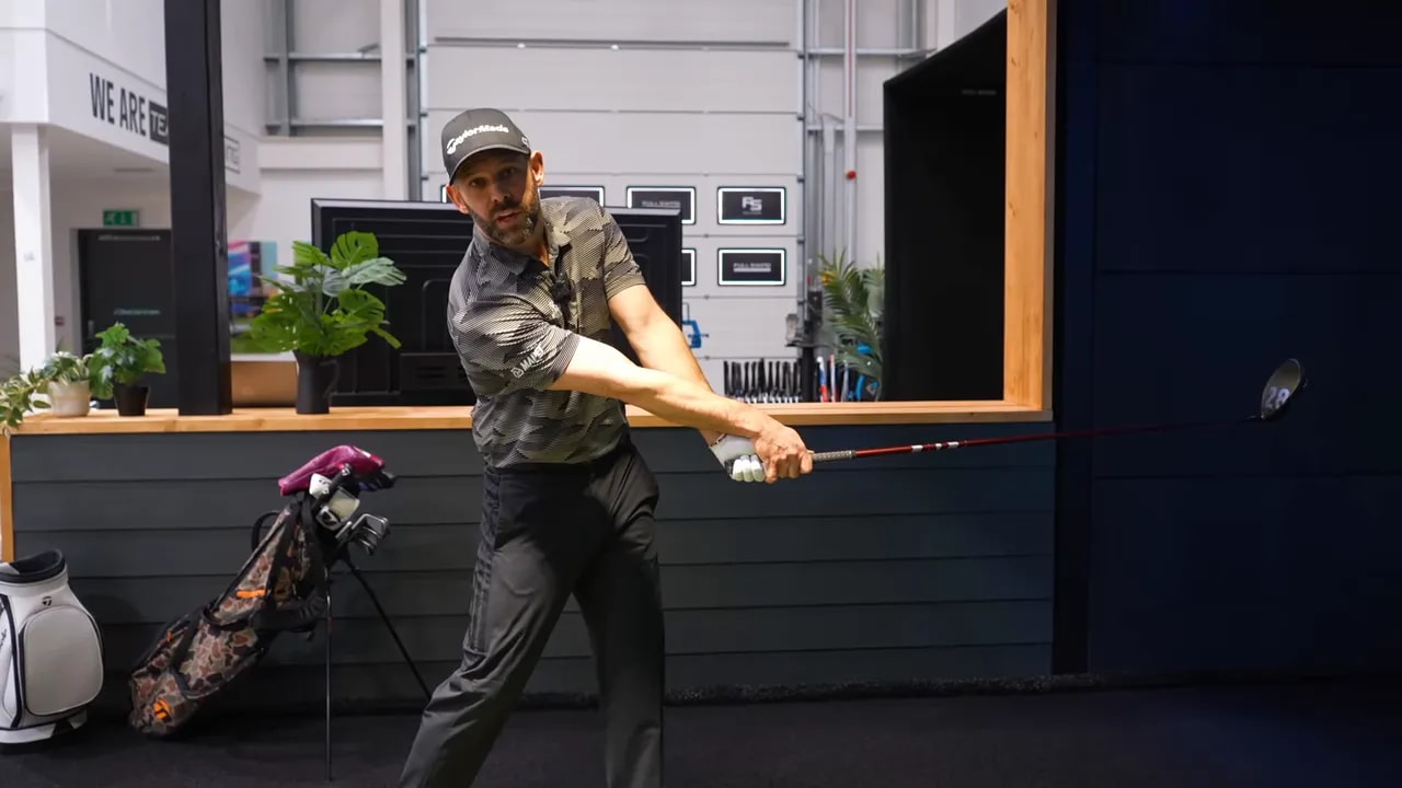 Face-on view of golfer just after impact with shaft level and lead hand rotated showing glove fingers