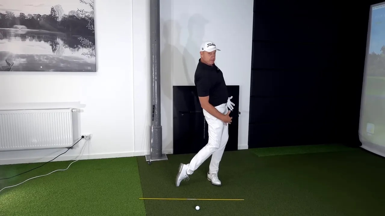 Golfer holding a palms-down 70s drill finish showing a clear lateral hip shift with the lead hip outside the lead ankle