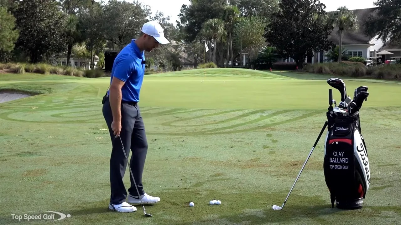 Golfer addressing ball near edge of green with club behind the ball demonstrating pitch setup