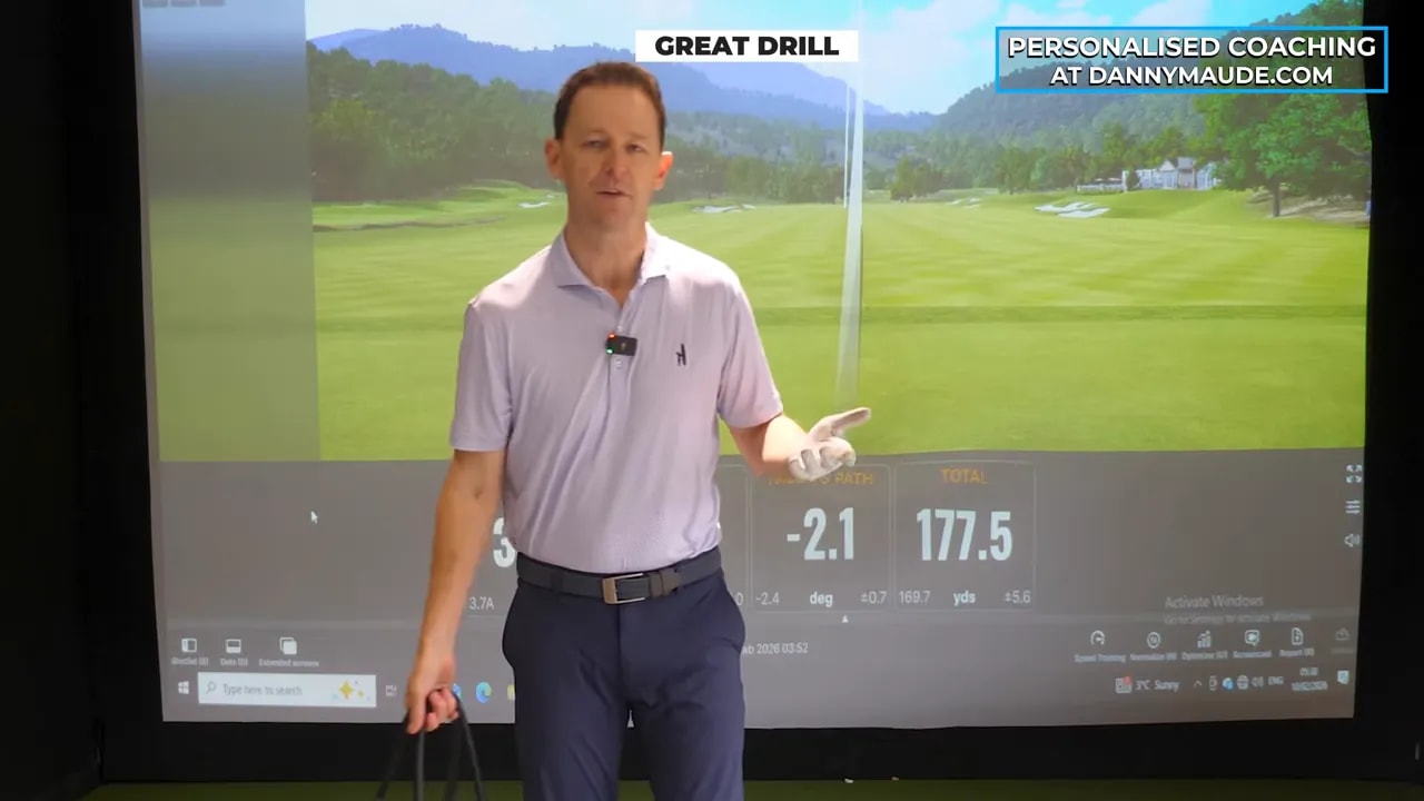 Golf coach demonstrating the shopping-bag counterbalance drill indoors in front of a simulator screen