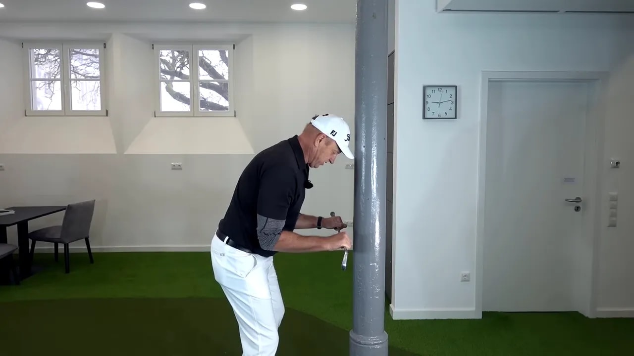 Golfer performing wall drill with shoulders close to a wall post to maintain lead-side tilt