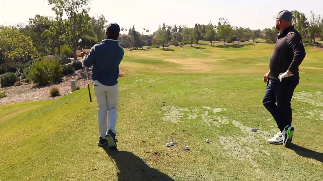Golfer in follow-through after a wedge shot, club high with weight on the lead foot