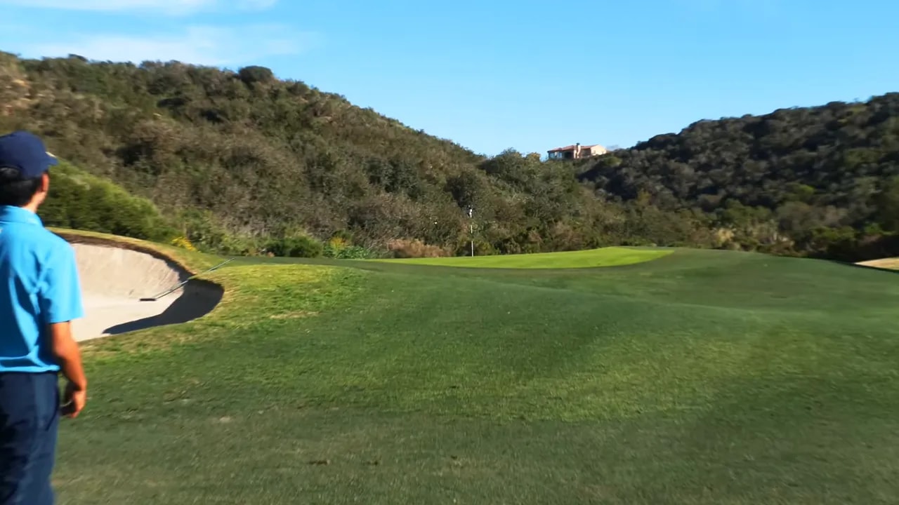 View of the green showing the pin, a left-side bunker and approach slopes
