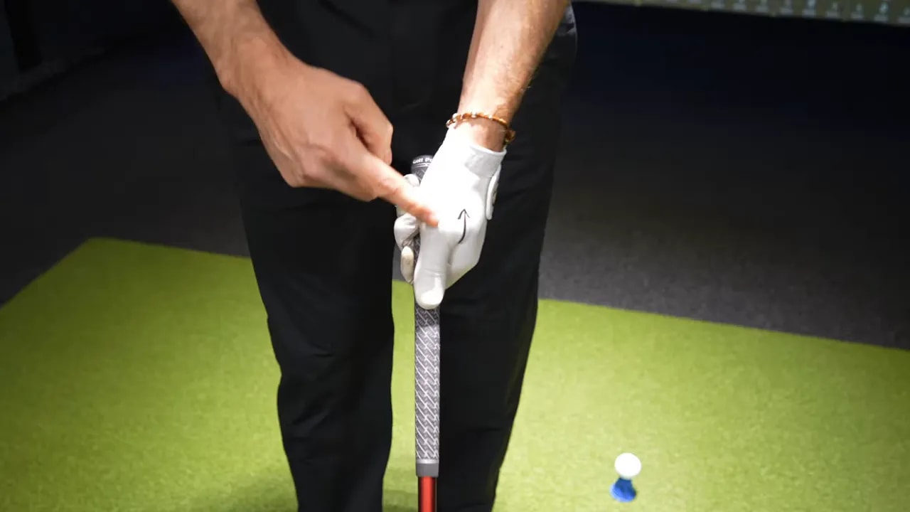 Close-up of gloved lead hand holding a driver grip with grip-check arrow cue