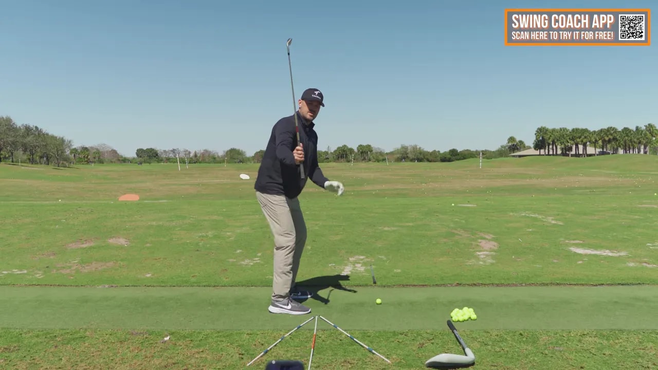 Golf coach demonstrating effortless power swing with alignment sticks on the practice range
