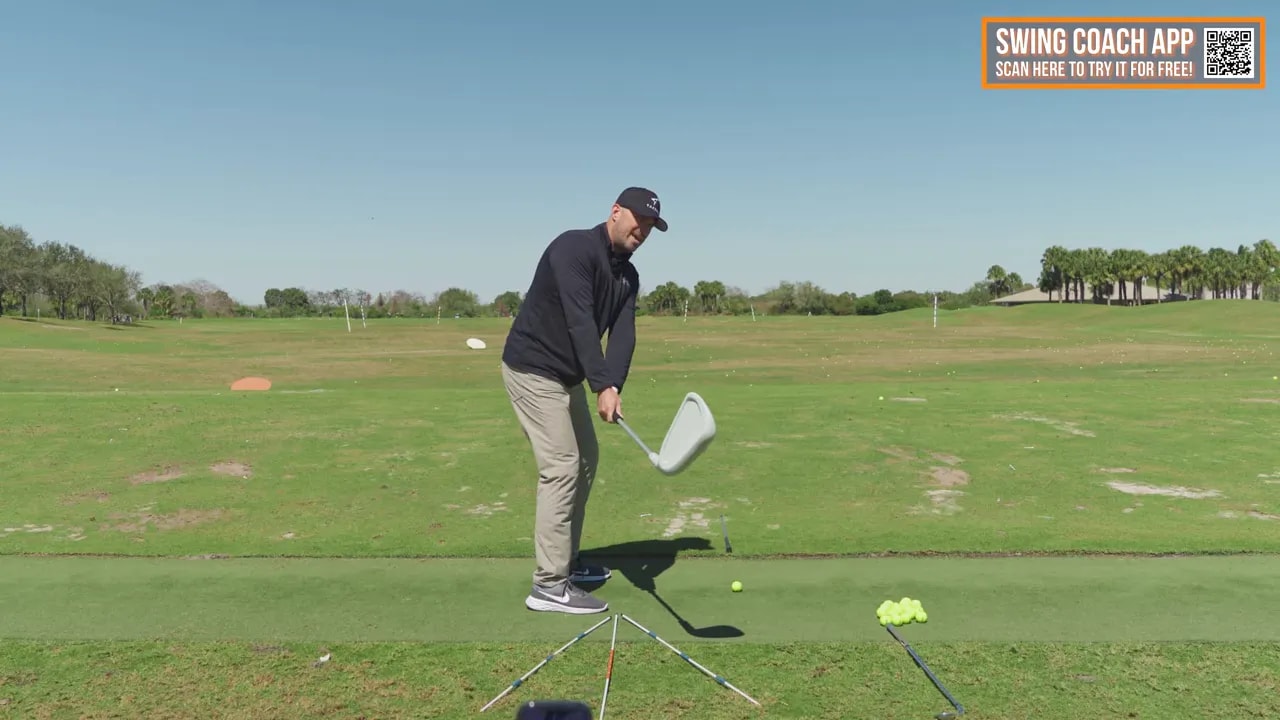 Golfer demonstrating shaft-path feel with alignment sticks for effortless power swing drill