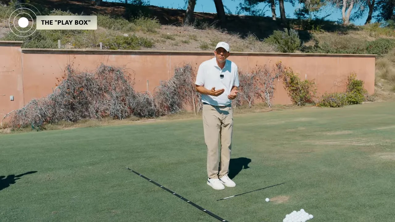Golf instructor standing in the play box on the practice green with the play box label
