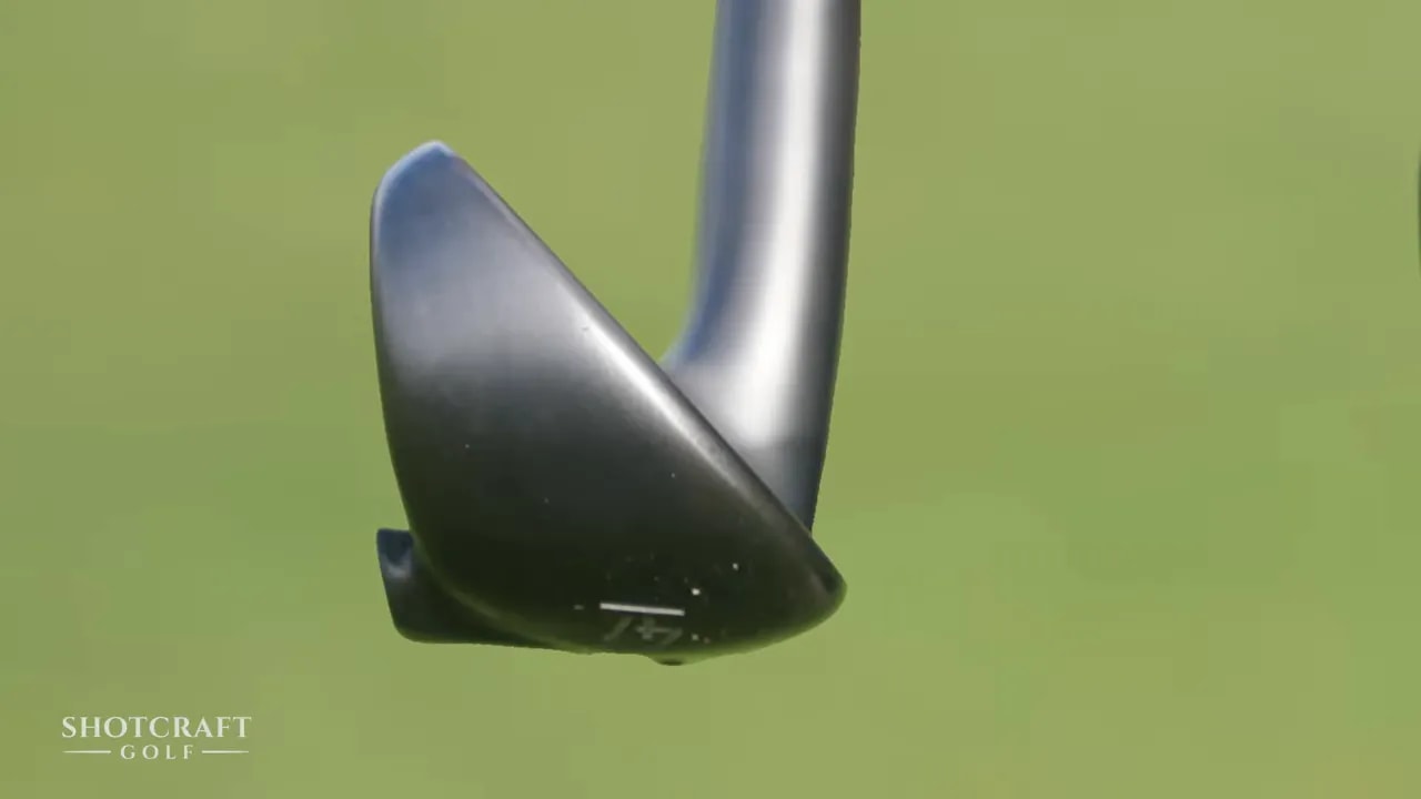 Close-up of a golf wedge head leading edge that can grab or glide through turf