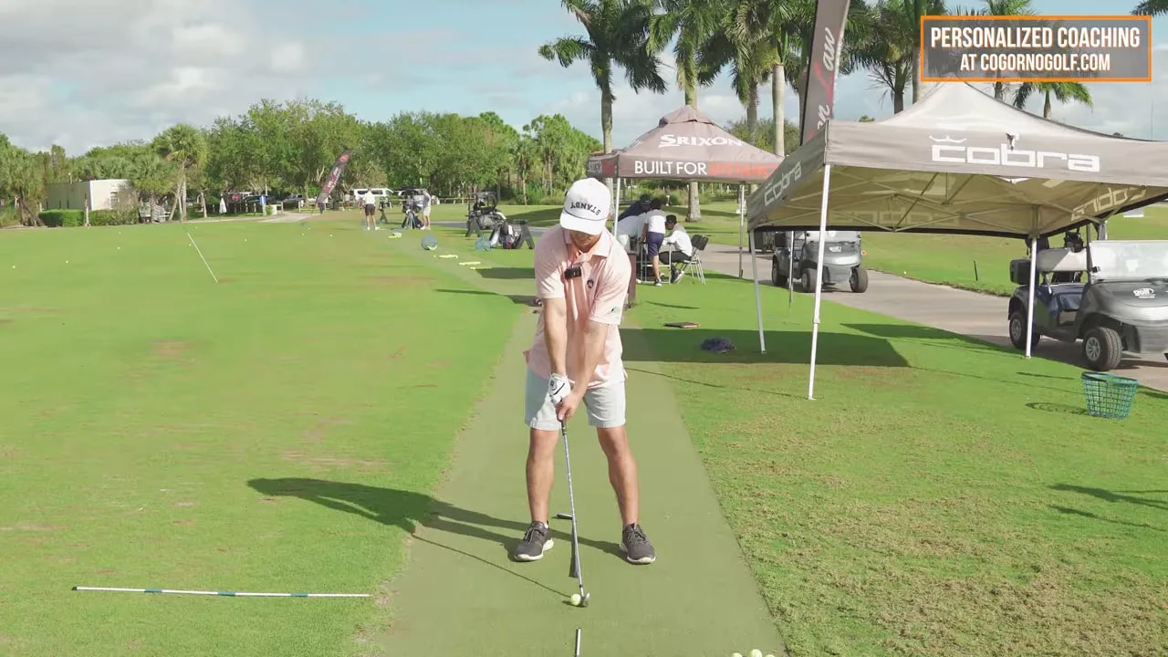 Golfer at address on a practice range with alignment line and ball for punch-and-twist drill reps