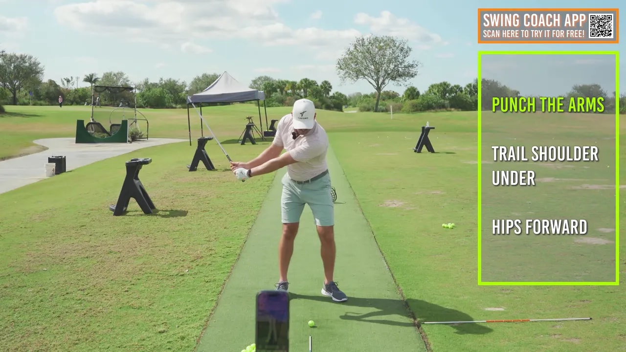 Front view of a golfer mid-finish with hands extended away and an instructional text box listing 'Punch the arms, Trail shoulder under, Hips forward'