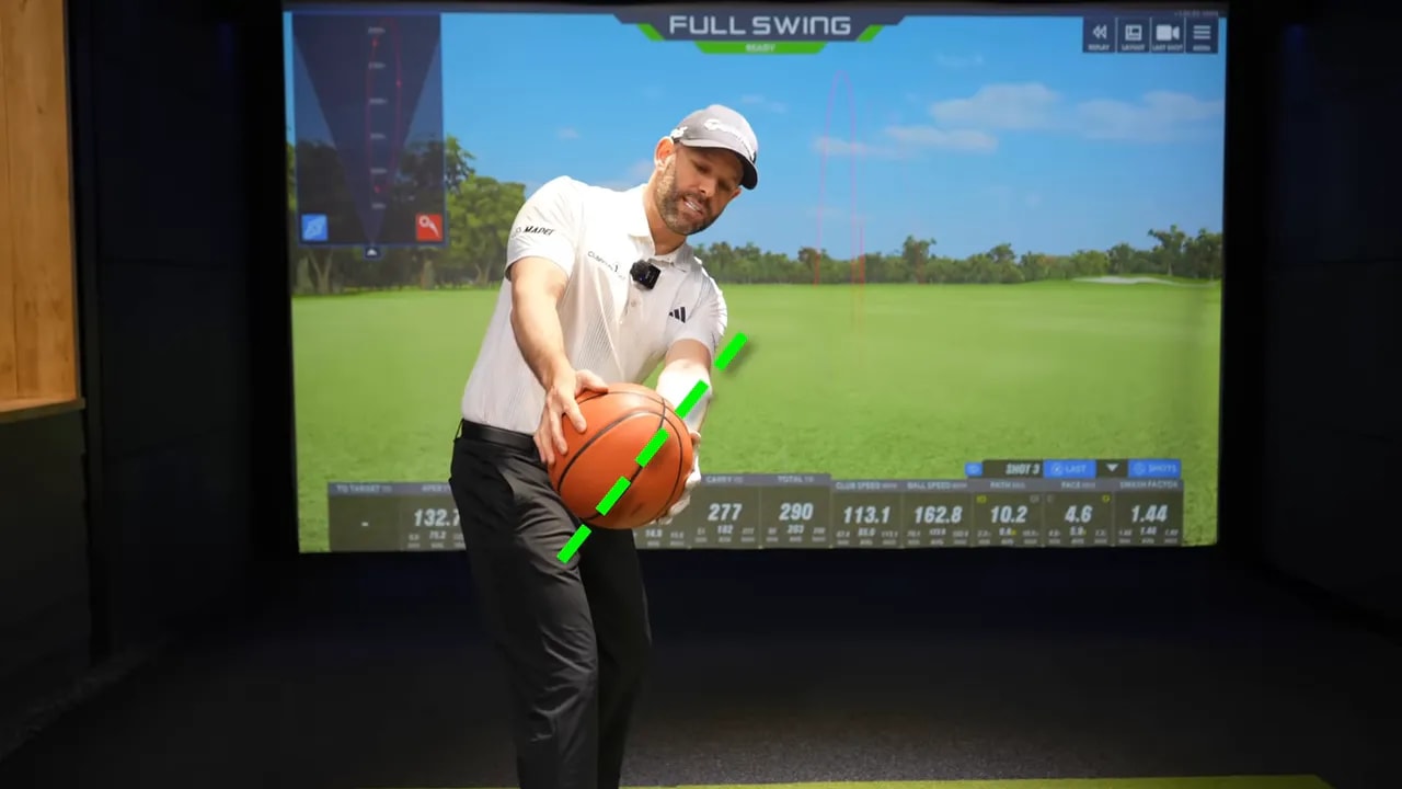 Instructor holds a basketball reference with green guide marks to explain the square-to-the-arc model