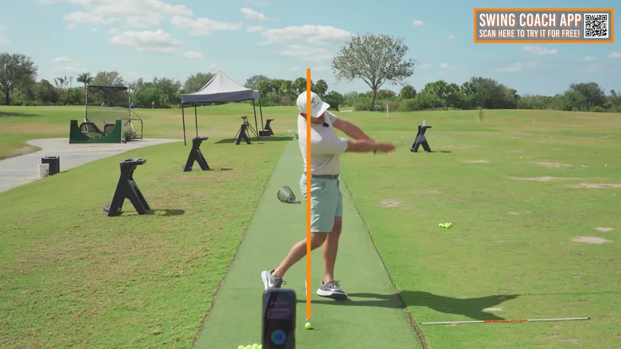 golfer at impact recorded on phone with orange vertical reference line down the ball line