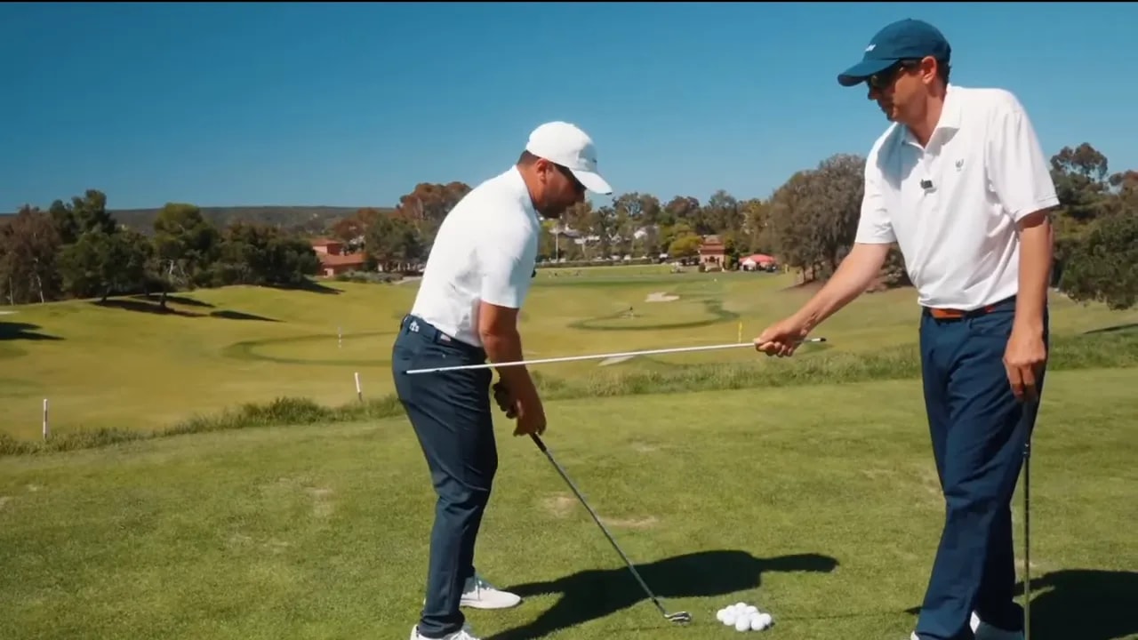 Golf instructor demonstrating club shaft positioned in front of player's forearm at address to show proper hinge and hand path.