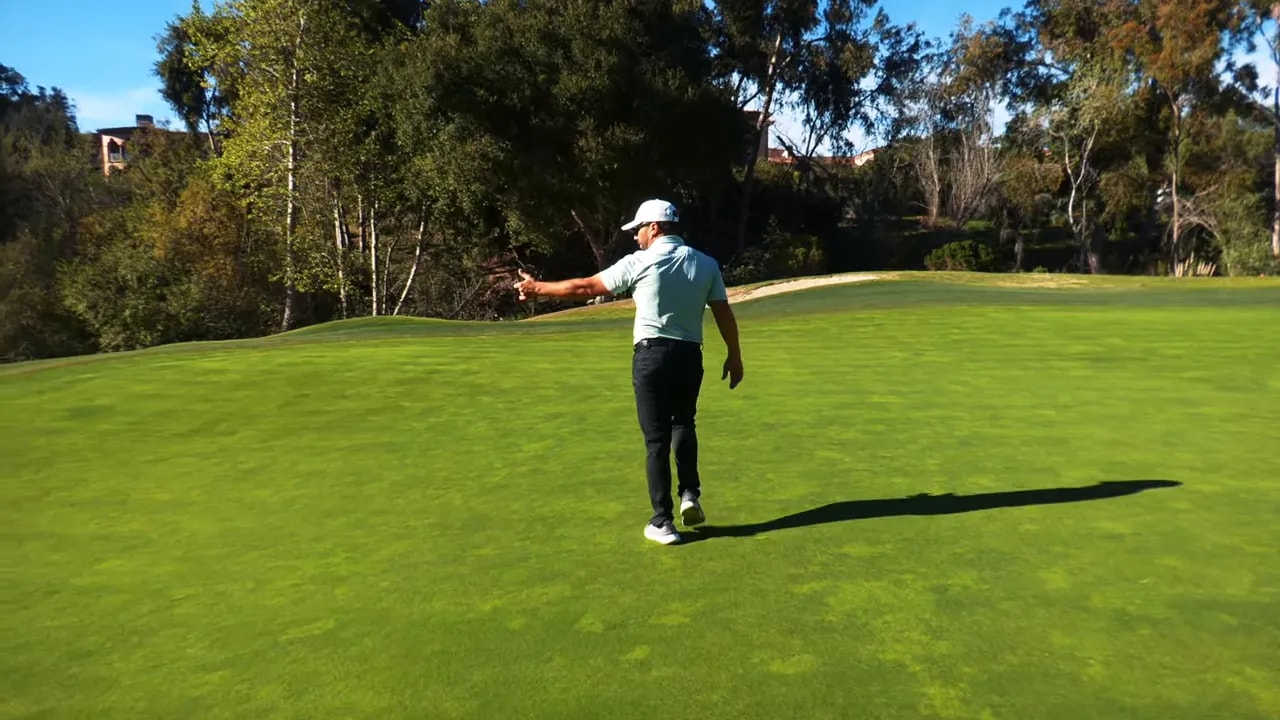 Instructor on the putting surface pointing to a target line while standing on the green