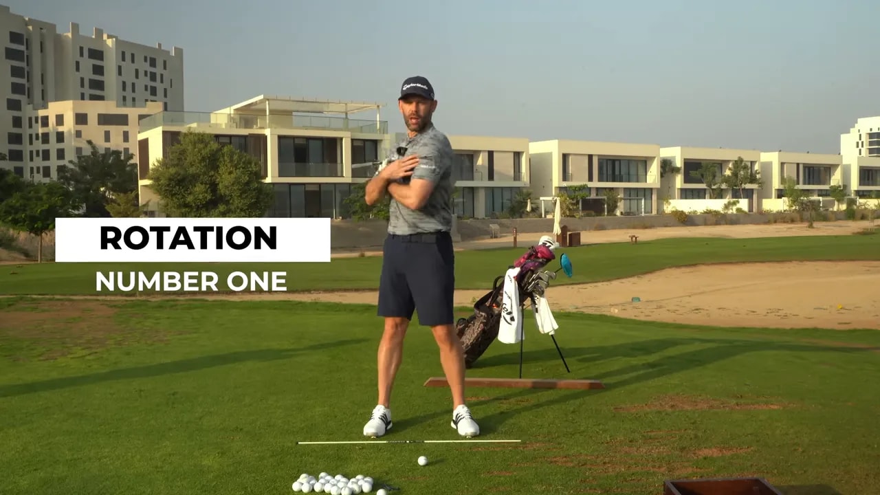 Golf coach demonstrating rotation with club across his shoulders and on-screen 'ROTATION' text