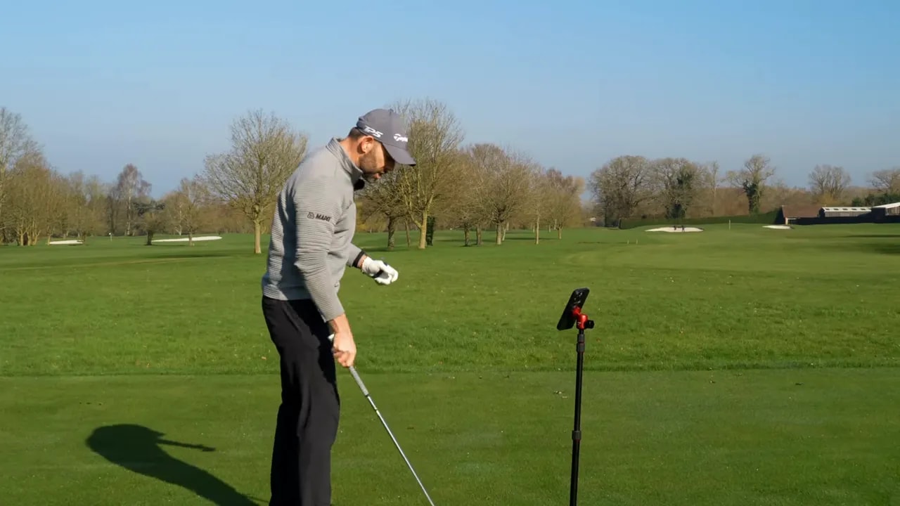 Golfer practicing a step-and-turn downswing sequencing drill with launch monitor on the fairway