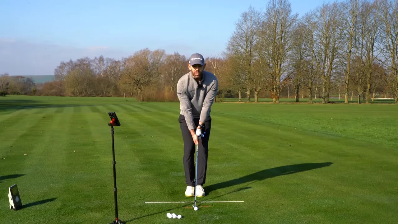 Golfer holding the step drill position with pressure shift and alignment line on the fairway