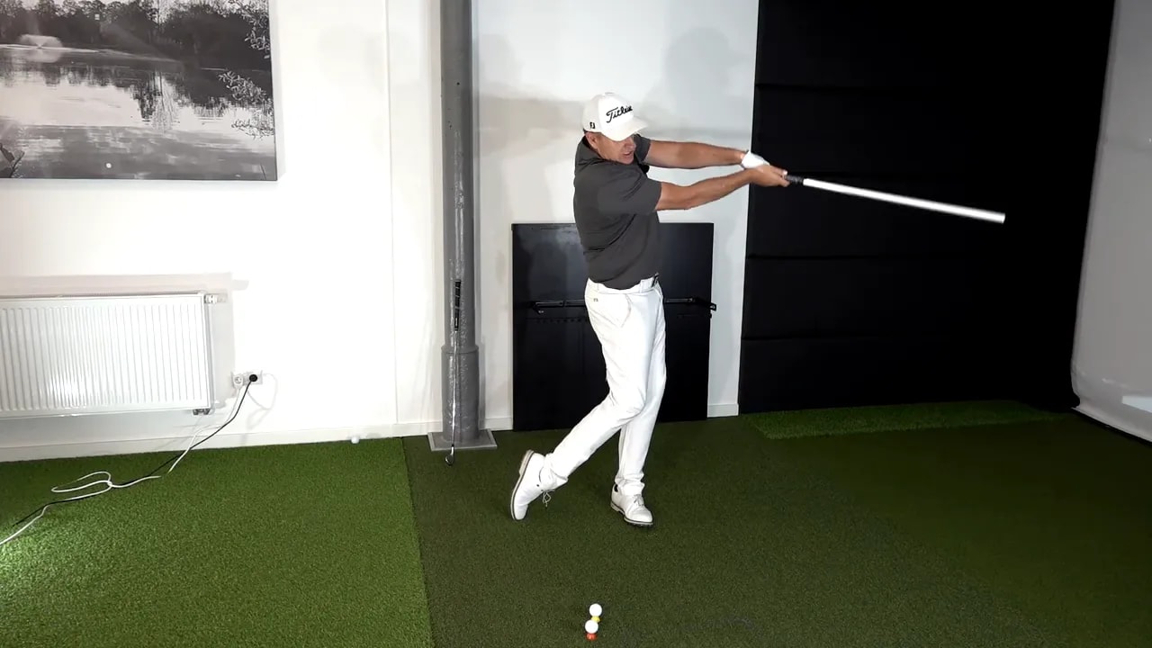 Golfer demonstrating wrist hinge position during indoor golf practice