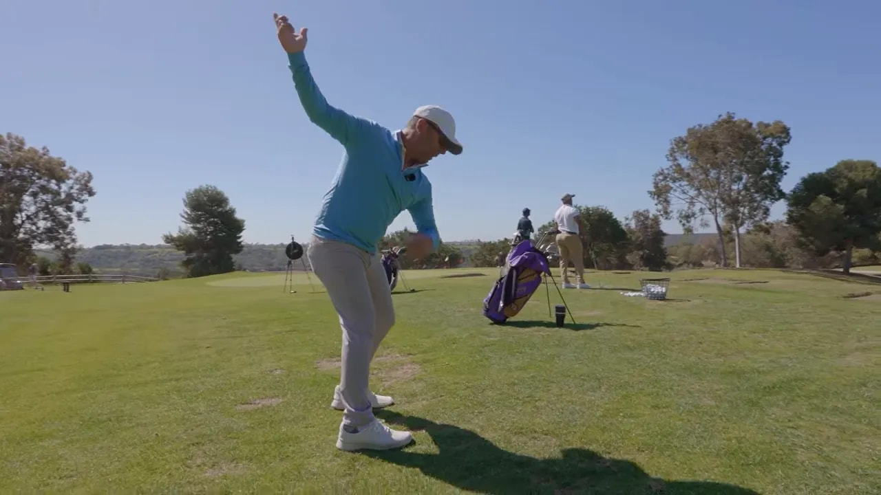 Golf instructor demonstrating athletic rotation through impact with grip setup on the driving range