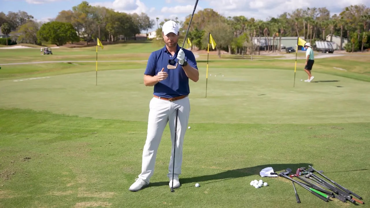 Golf instructor presenting a chipper and discussing face height for chipping