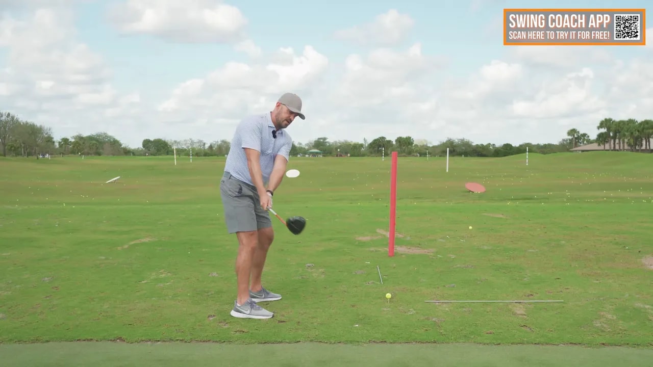 Golfer demonstrating driver swing position with the club near last parallel using range alignment markers