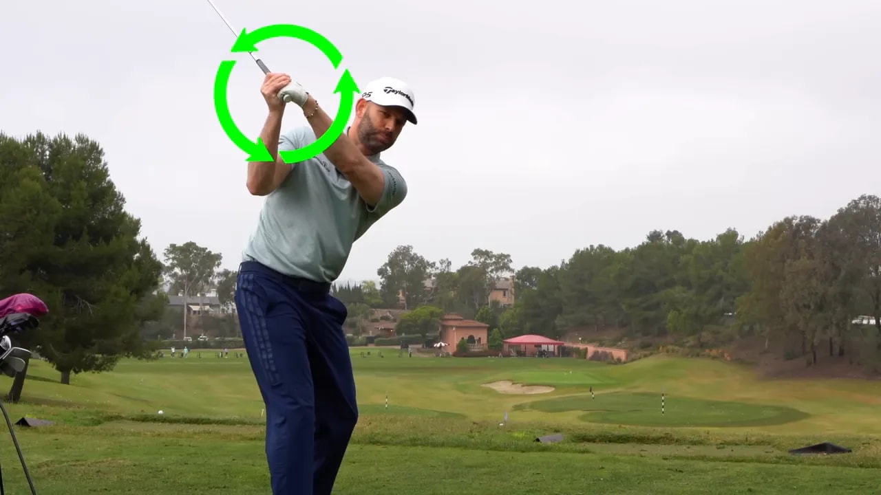 Golf instructor demonstrating clubface twist using a green arrow and rotation overlay on a driving range