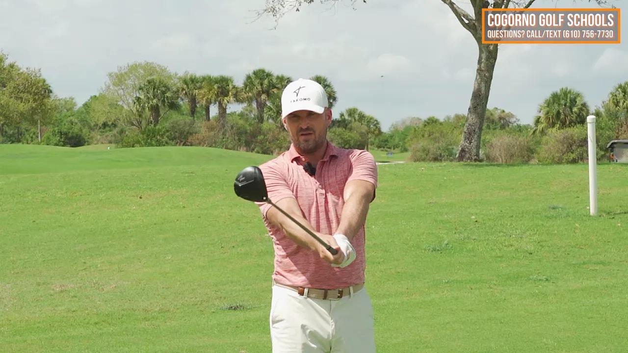 Coach demonstrating fairway wood extension cue just past the ball with forward belt buckle movement