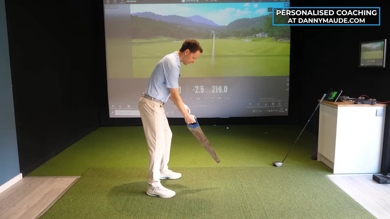 Coach leaning forward demonstrating hands and club position for proper driver release timing in a simulator