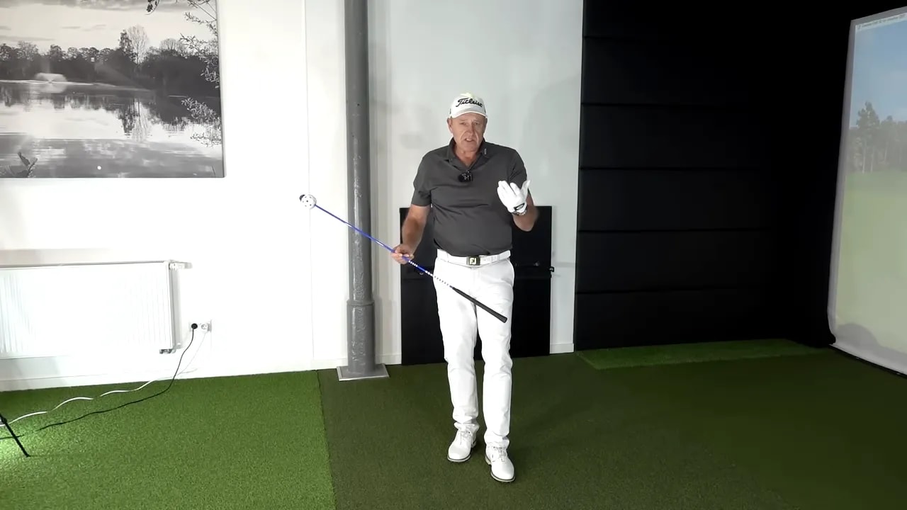 Golfer demonstrating controlled hands through impact with a blue training line for better clubface squaring