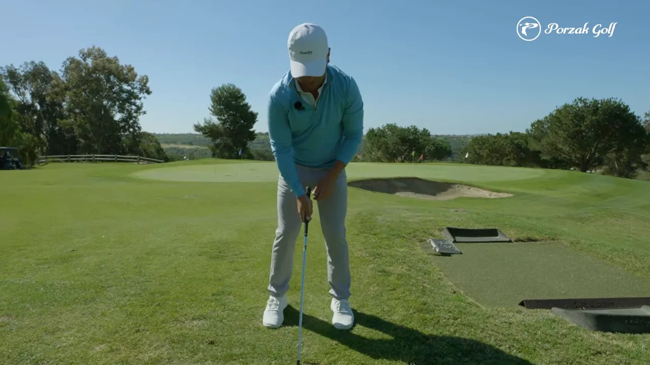 Golfer demonstrating a controlled setup position for short compression practice with an iron or wedge