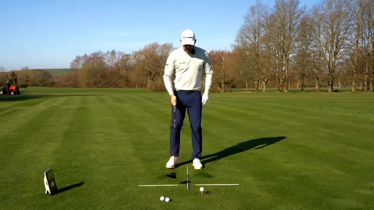 Golfer at address with a visual line behind the ball to set the driver low point