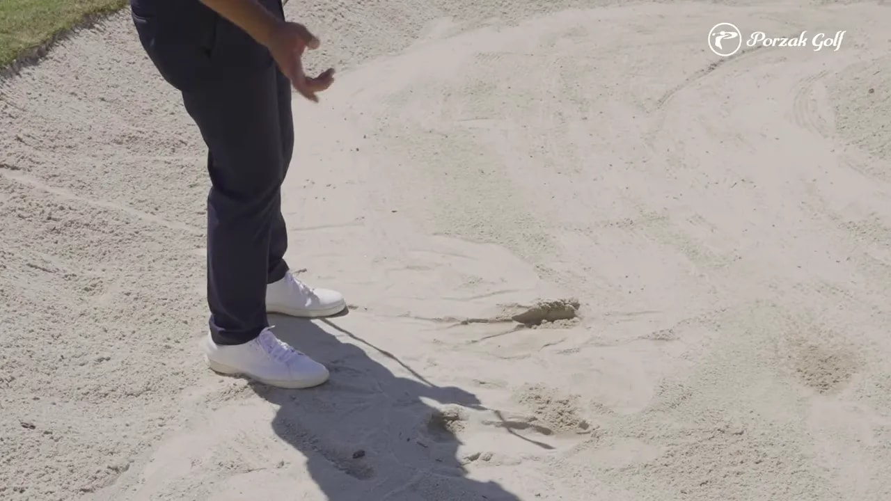 Fairway bunker divot and sand disturbance showing ball-first strike