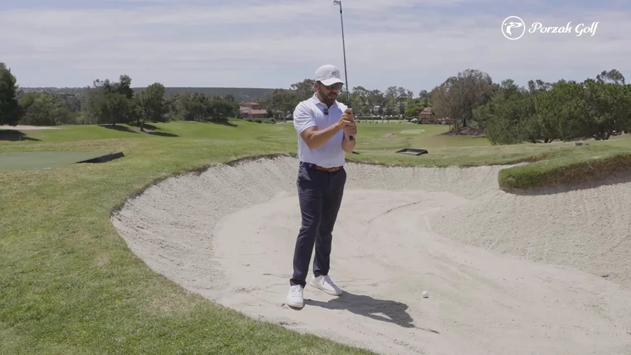 Golfer demonstrating fairway bunker shot setup with ball visible in the sand