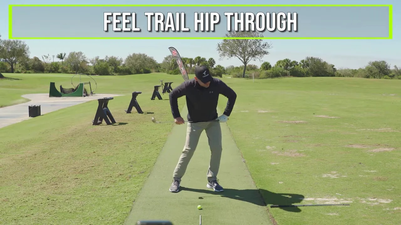 Trail hip through drill with on-screen cue while golfer practices on range