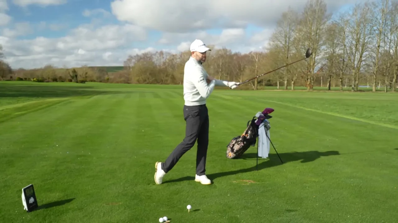 Golfer swinging with a flowing wrist feel to counter locked wrists during a golf distance lesson