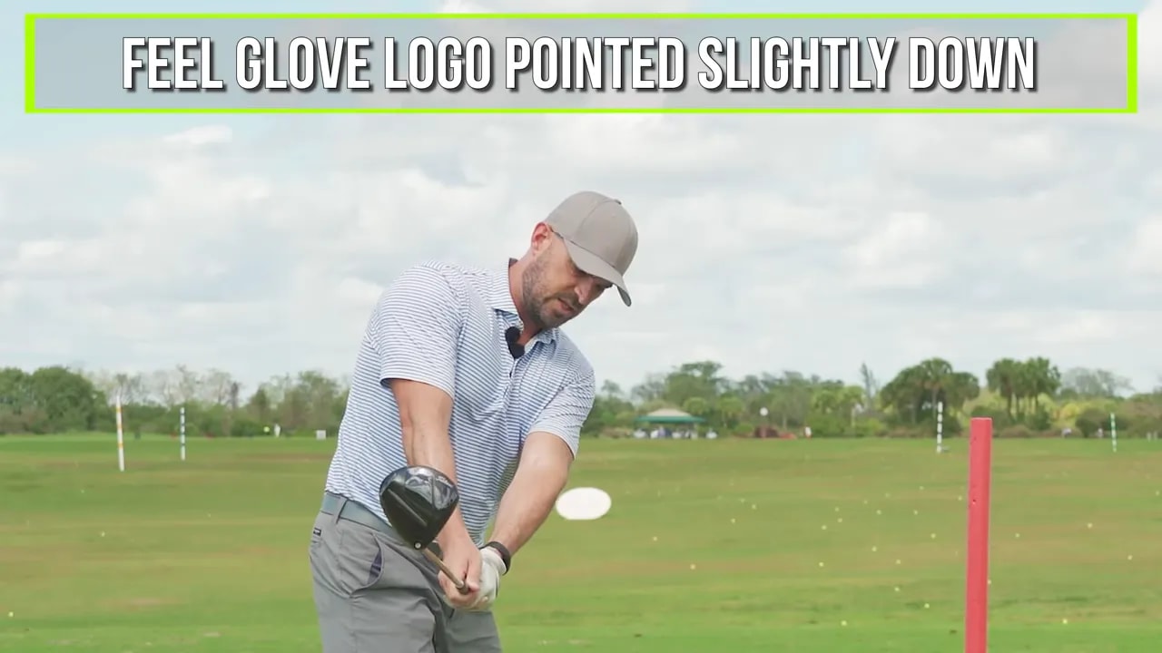 Close view of a golfer demonstrating the glove logo pointed slightly down cue with a driver on a range