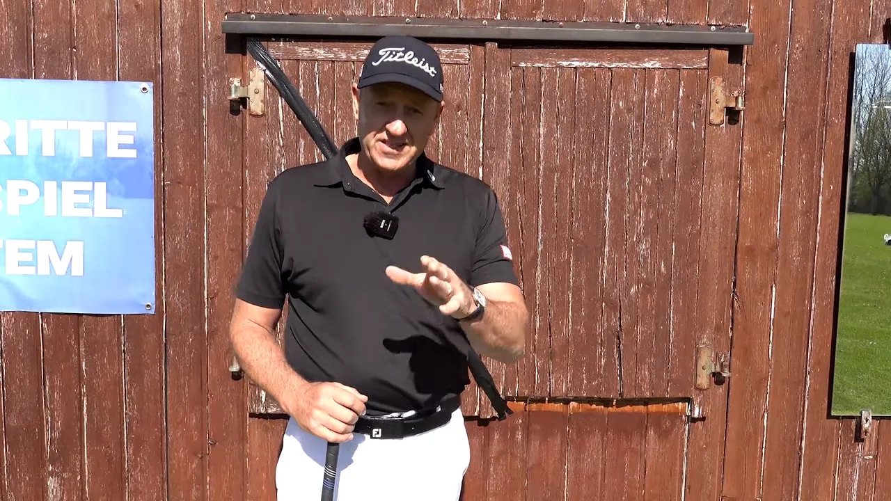 Golf coach speaking and demonstrating the 55-degree rule shoulder plane concept with a club