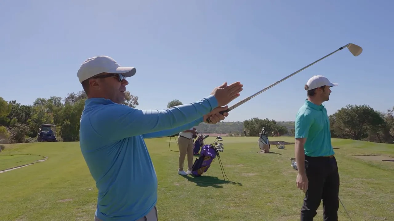 Instructor pointing to demonstrate golf grip setup and club presentation at the range