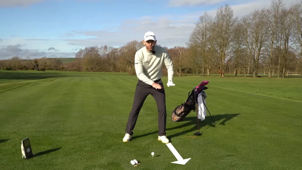 Golf instructor demonstrating a push-away cue toward the lead foot with an arrow on the range