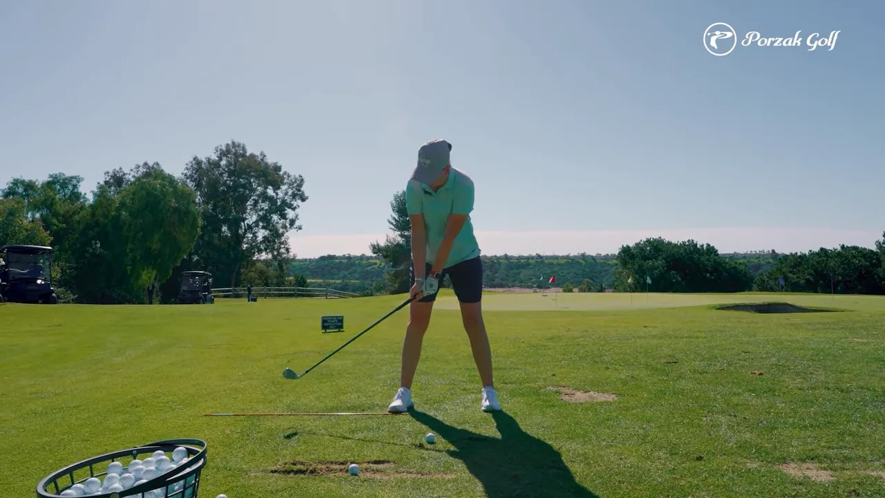 Golfer at address on a golf range holding a club with an alignment reference line on the turf