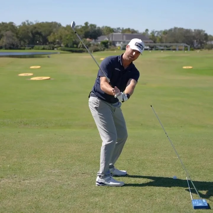 Golfer checking trail shoulder position halfway down the downswing on a golf course