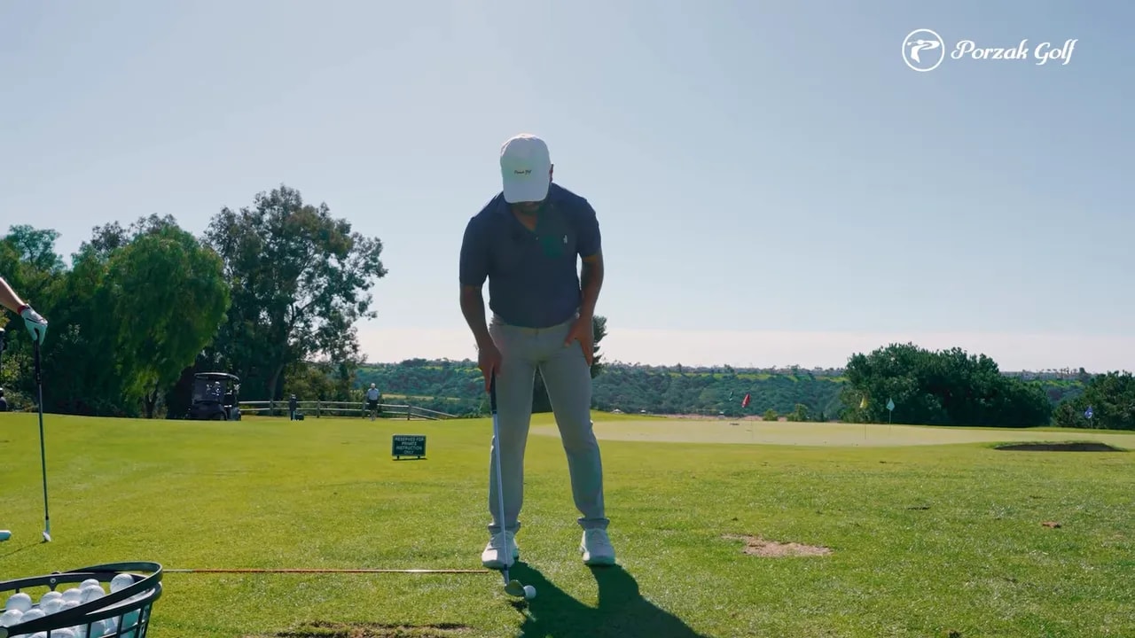 Golfer demonstrating setup posture with hips over ankles on a golf range