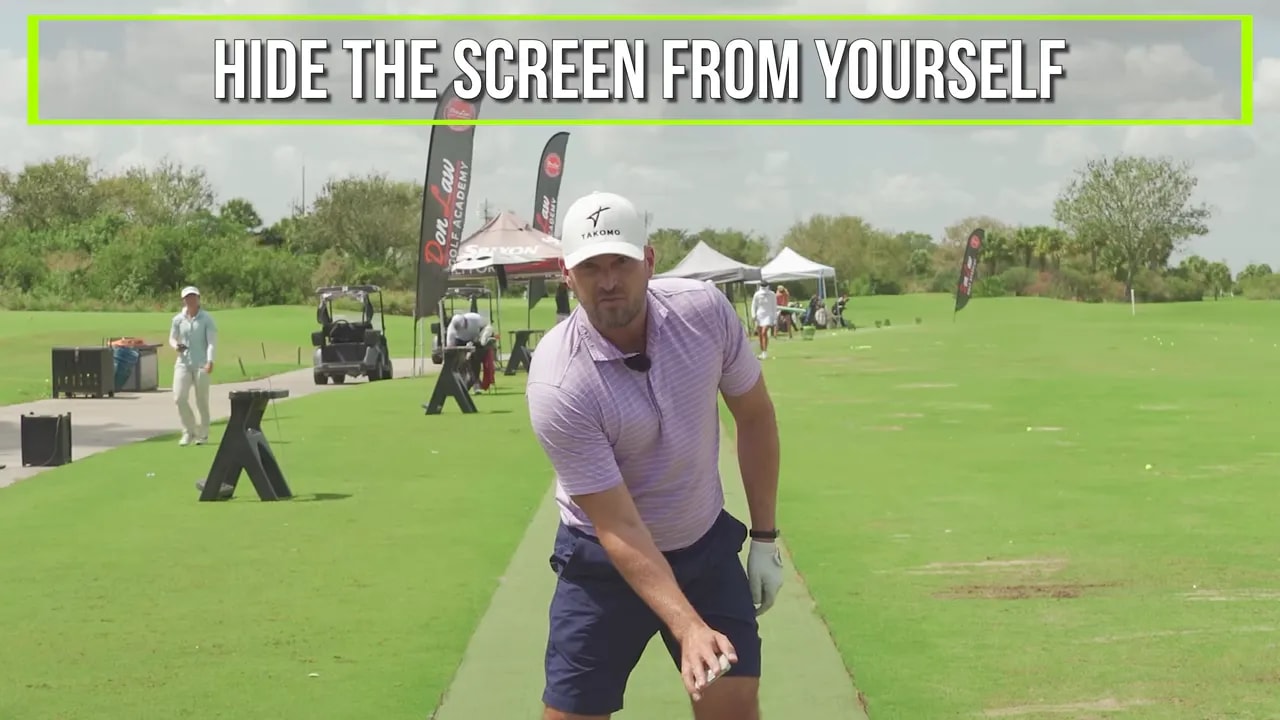 Instruction shot on a golf range showing the cue to hide the screen from yourself during wrist-forward impact